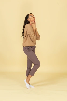 Three-quarter view of an attractive dark-skinned young lady touching her neck