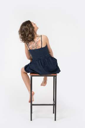 Femme avec dos tatoué assis sur un tabouret de bar