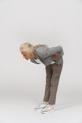 Vista lateral de uma senhora idosa de terno se curvando