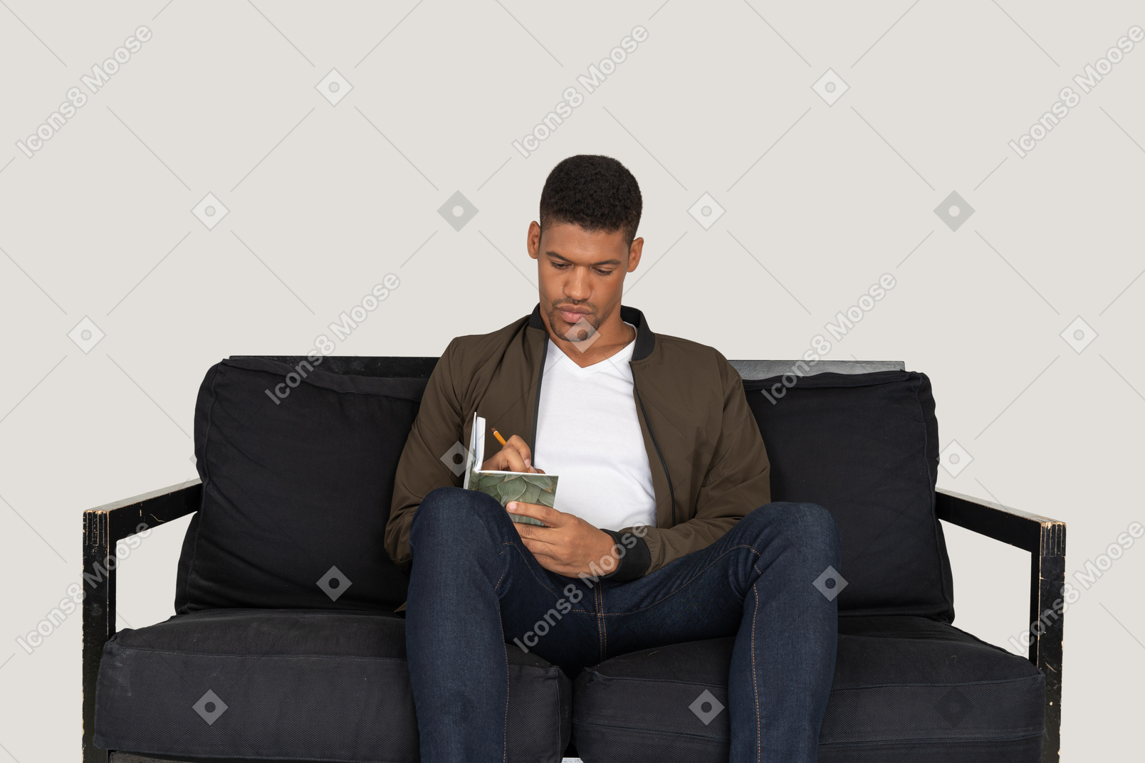 Vista frontal del joven sentado en un sofá y tomando notas