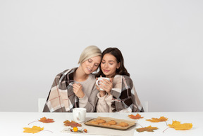 Young women drinking coffee and leaning on each other