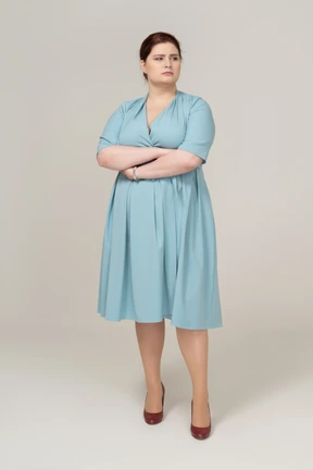 Front view of a woman in blue dress posing with crossed arms