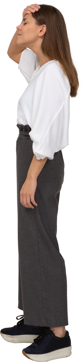 Vue latérale d'une jeune femme en vêtements de bureau touchant le front