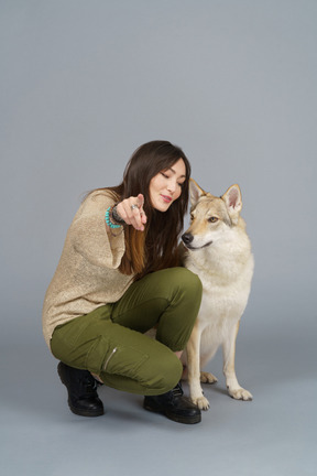 Pleine longueur d'une femme maître pointant la caméra et regardant son chien