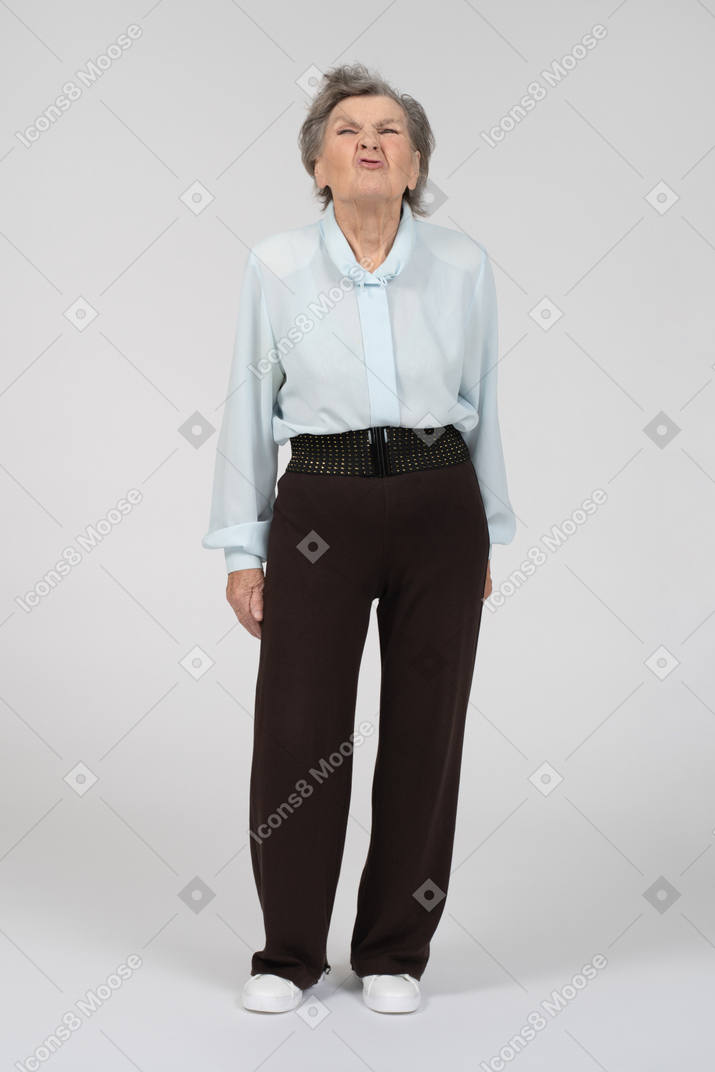 Vista frontal de una anciana con ropa formal haciendo muecas