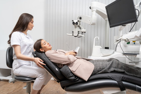 Vista frontal dentista hablando con su paciente travieso en un gabinete de hospital