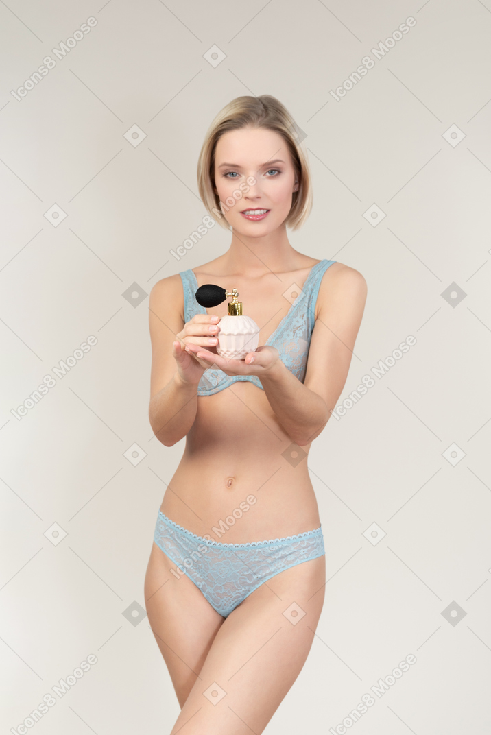 Sexy young woman in lingerie holding perfume atomizer