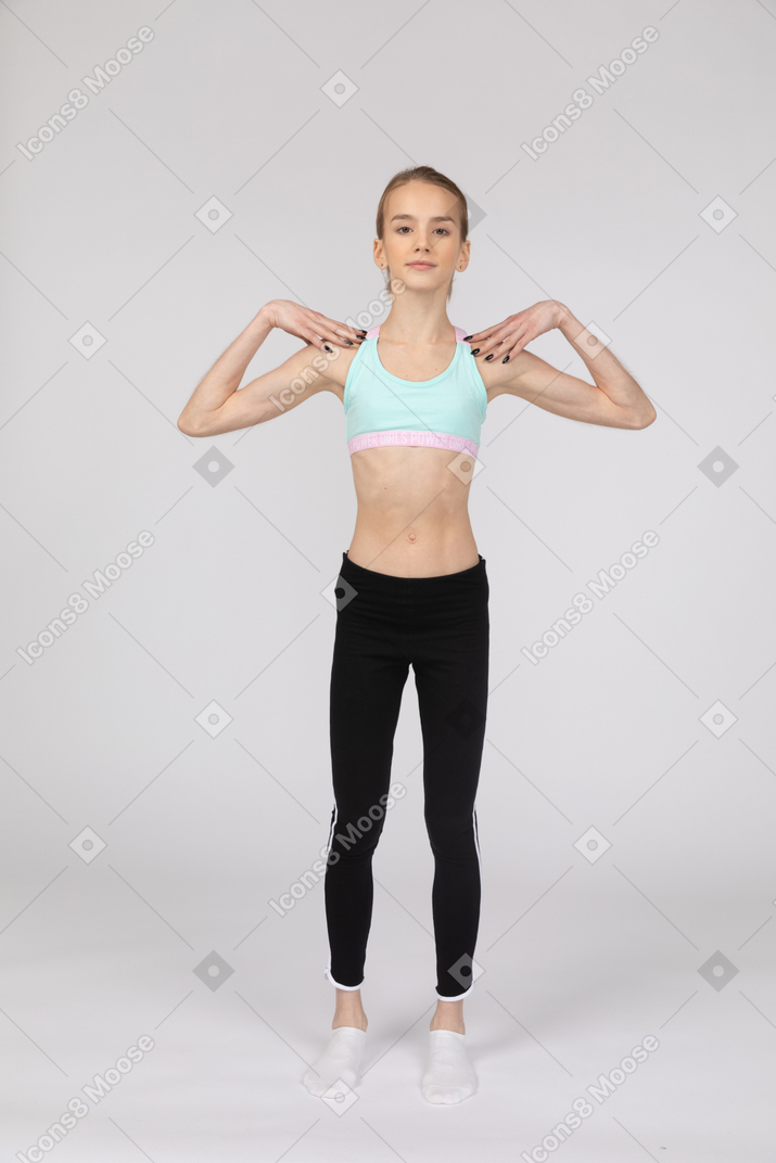 一个年轻的女孩，穿着运动服抚摸她的肩膀的前视图
