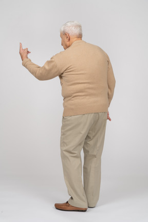 Vista traseira de um velho em roupas casuais, apontando para cima com um dedo