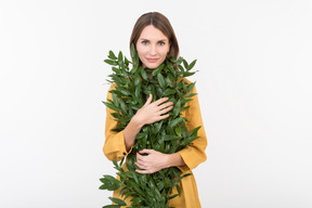 Mujer joven abrazando ramas verdes