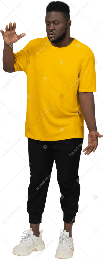 Vorderansicht eines jungen dunkelhäutigen mannes in gelbem t-shirt, das die größe von etwas zeigt