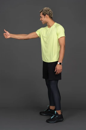 Side view of a dark-skinned young man showing a thumb up