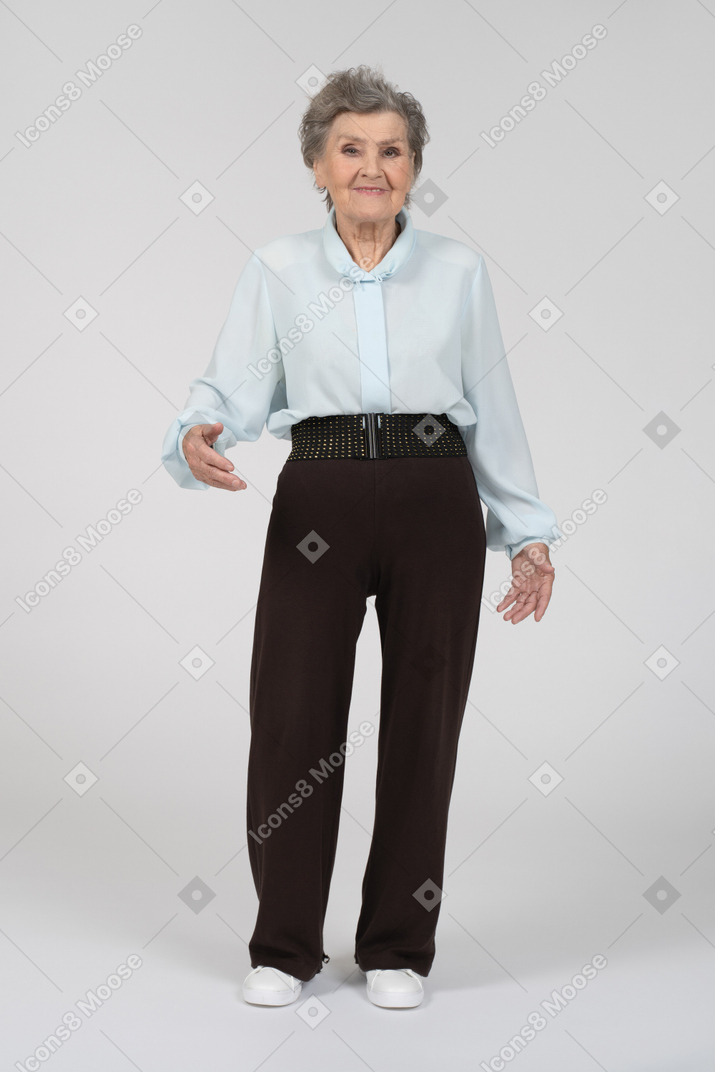 Front view of an old woman smiling and gesturing welcomely