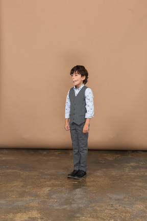 一个穿着西装的男孩站着不动做鬼脸的前视图