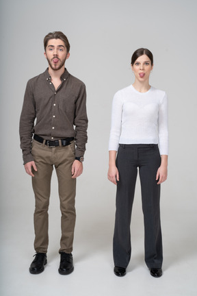 Front view of a young couple in office clothing showing tongue