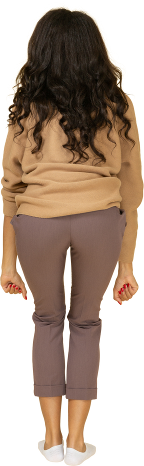 Vista posterior de una mujer joven de piel oscura levantando pesas