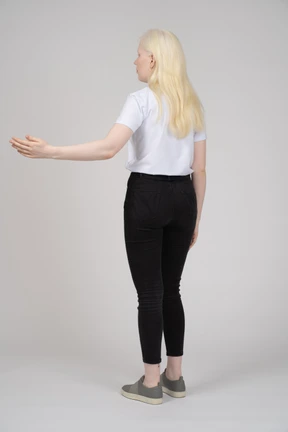 Back view of a young girl standing and holding up left arm