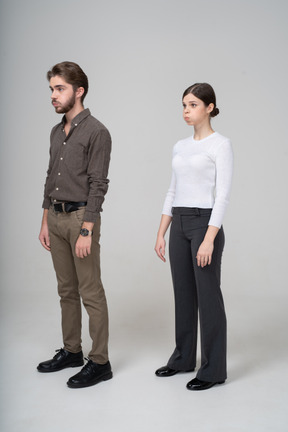 Vista de tres cuartos de una pareja joven en ropa de oficina soplando mejillas