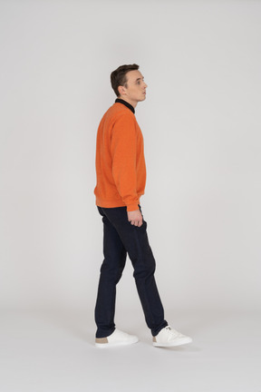 Young man in orange sweatshirt walking