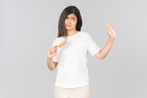 Dissatisfied young indian woman holding hairbrush