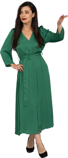 Vista frontal de uma jovem de vestido verde levantando a mão