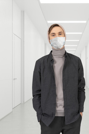 A man wearing a face mask standing in a hallway