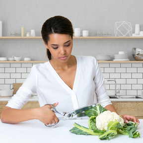 A woman cutting cauliflower leaves with scissors
