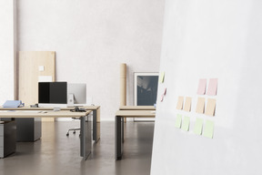 Office with work desks, computers and sticky notes on the wall