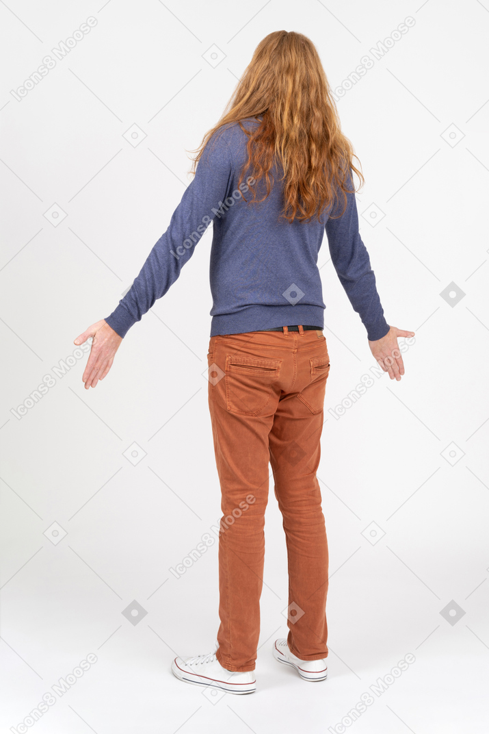 Vista posteriore di un giovane uomo in piedi con le braccia tese