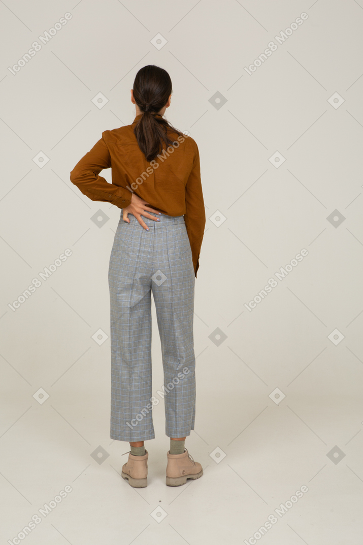 Back view of a young asian female in breeches and blouse touching back