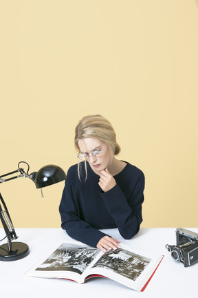 Junge frau sitzt am tisch und liest eine zeitschrift