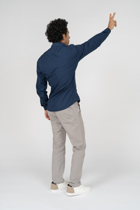 Rear view of a man in casual clothes showing v sign