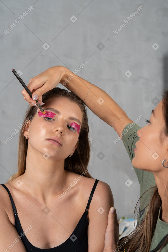 Vista frontal de uma mulher atraente fazendo sua maquiagem