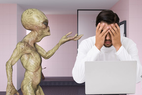 Alien standing next to frustrated man with laptop