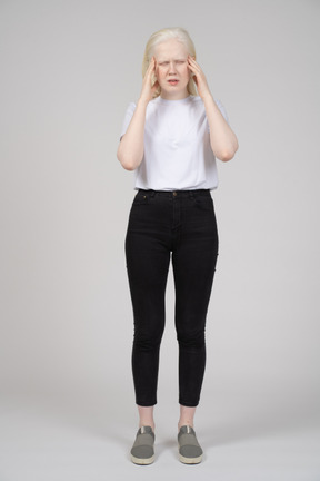 Front view of a standing young girl touching her hand with both hands