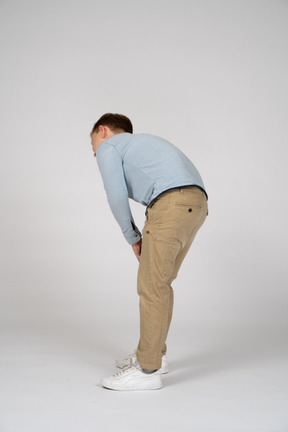 Side view of a boy bending down and touching hurting knee