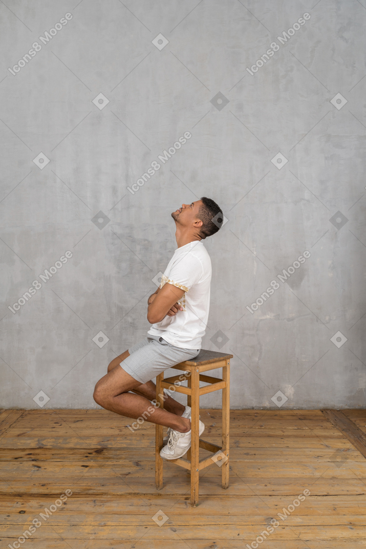 Homem sentado com os braços cruzados e olhando para cima