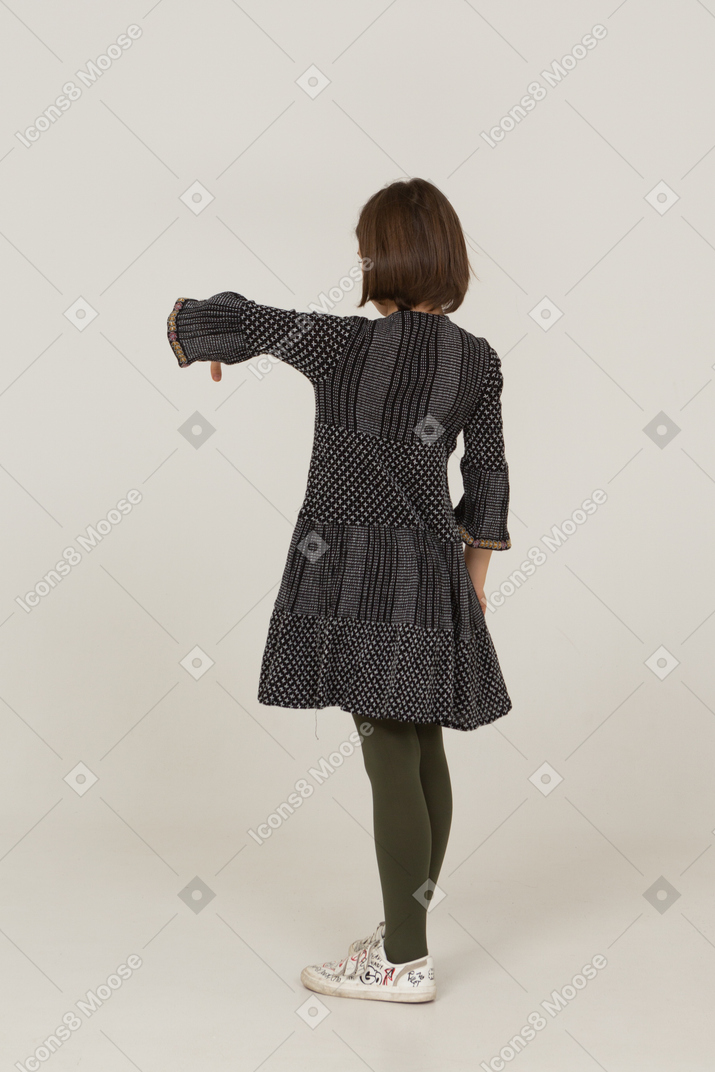 Three-quarter back view of a little girl in dress showing thumb down
