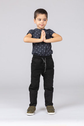 Vista frontal de um lindo menino fazendo gestos de oração