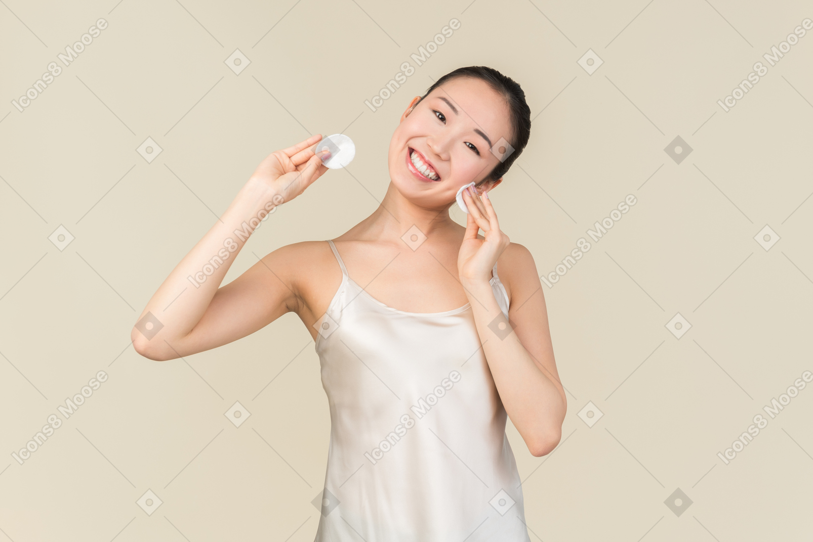 Laughing asian girl cleaning her face with cotton pads