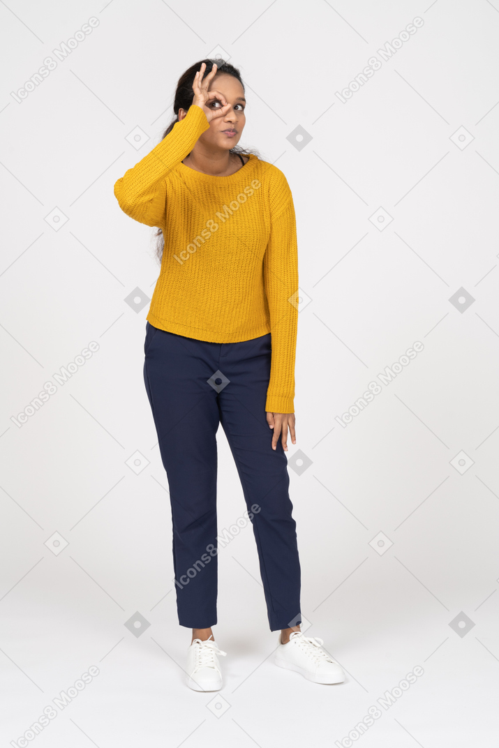 Vista frontal de una niña en ropa casual mirando a través de los dedos