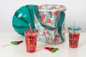 더운 여름 휴가를위한 최고의 레시피로 피크닉 음식이 담긴 보온 가방, 물에서 즐거운 시간을 보낼 수있는 풍선 장난감, 그 위에 음료수