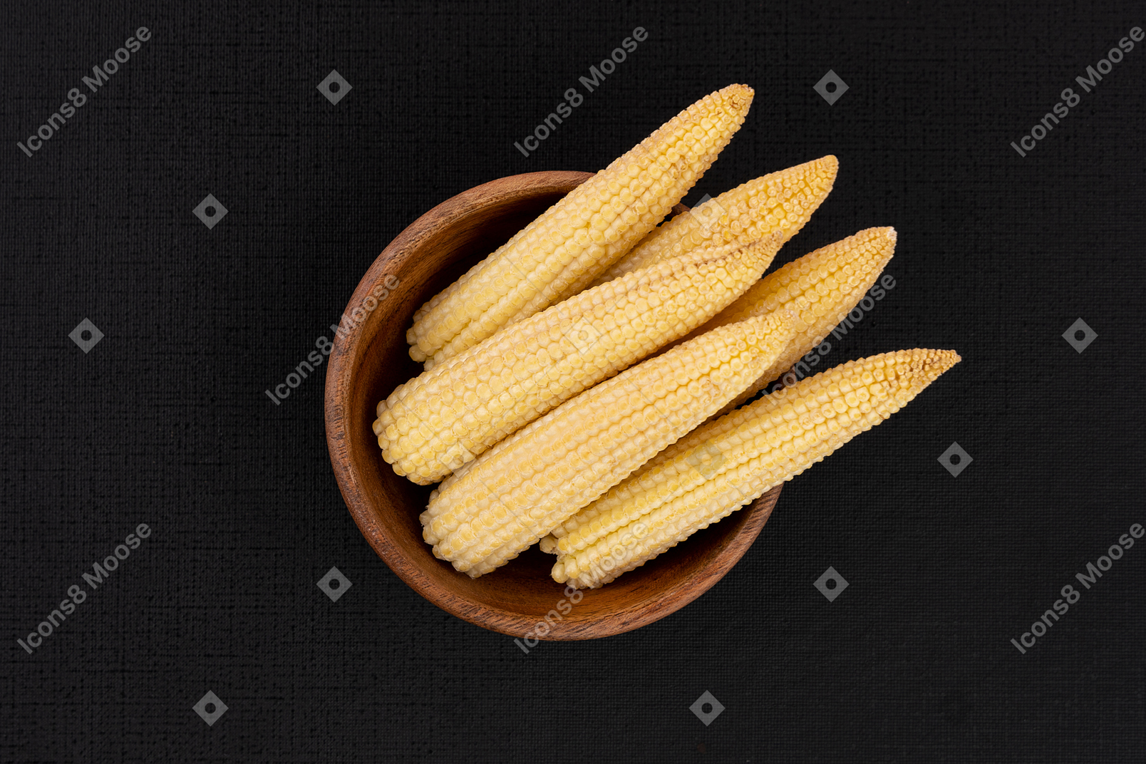 Brown bowl with baby corns on black background
