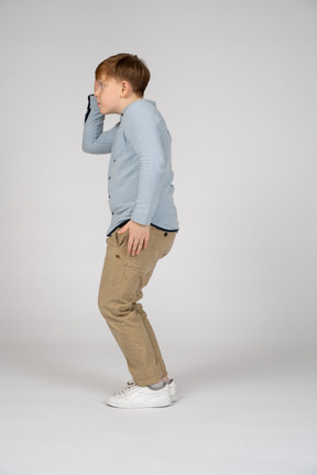 Side view of a young boy scratching his head