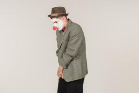 Male clown standing half sideways and wrapping up in jacket