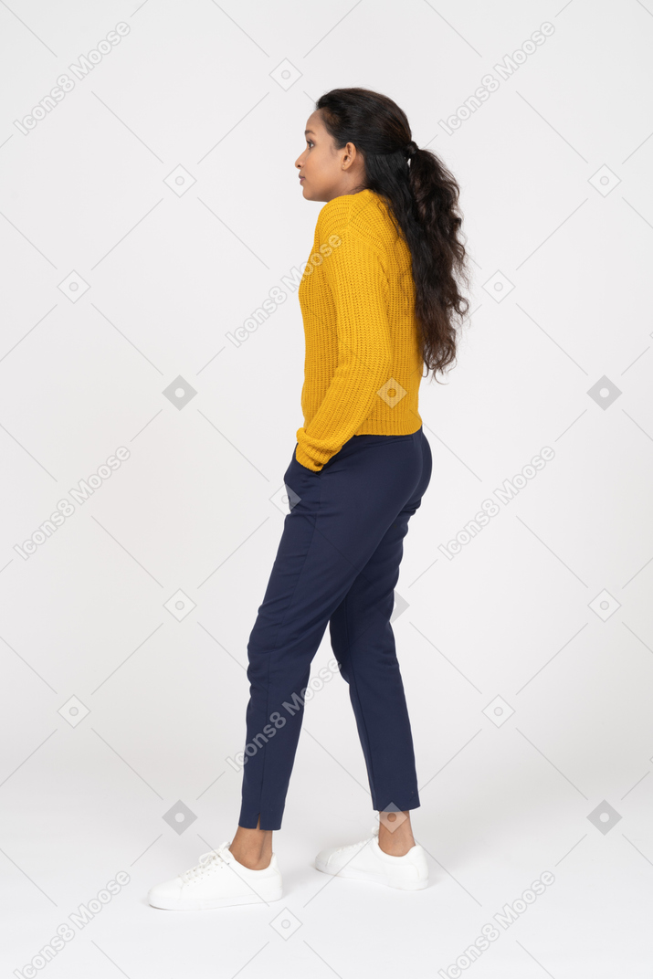 Side view of a girl in casual clothes posing with hands in pockets