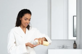A woman in a bathrobe is holding a bottle