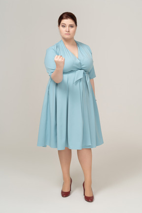 Front view of a woman in blue dress showing fist