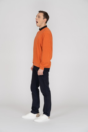 Jeune homme en pull orange debout