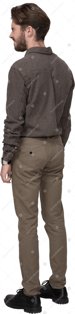 Vista posteriore di tre quarti di un giovane uomo dispiaciuto con una smorfia in abiti da ufficio